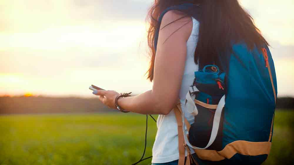 Žena je na výletě v přírodě a v ruce drží smartphone a powerbanku_02