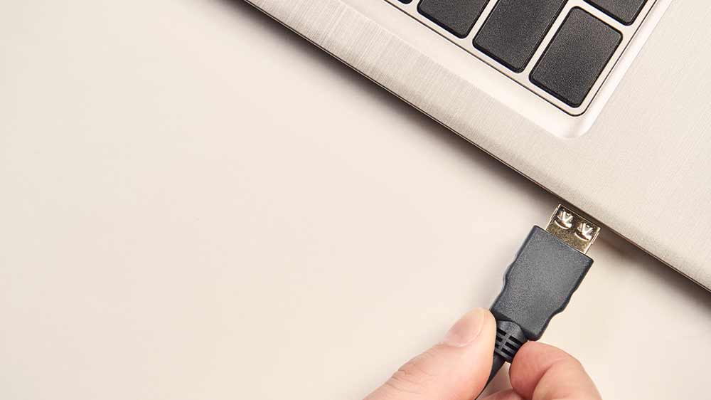 Človek zapojujúci HDMI kábel do notebooku_02