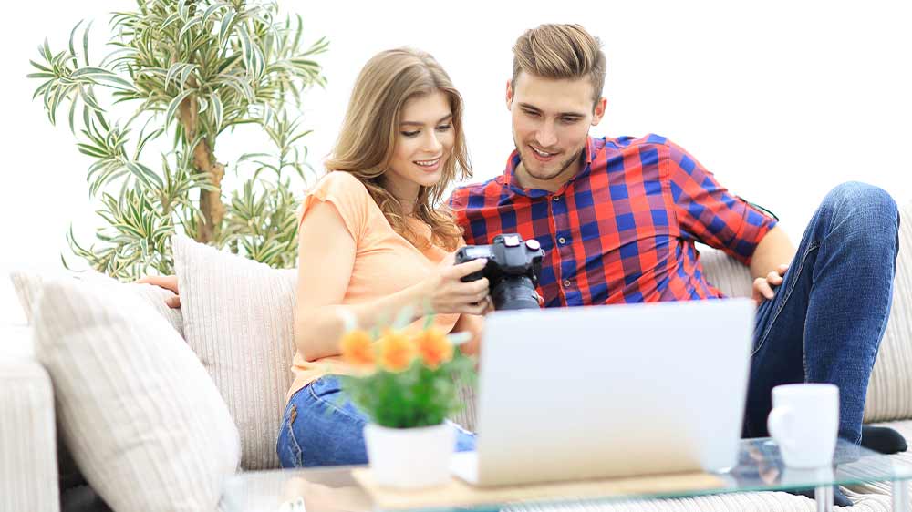 Žena s mužem sedí na pohovce u notebooku a prohlížejí fotografie ve fotoaparátu_04