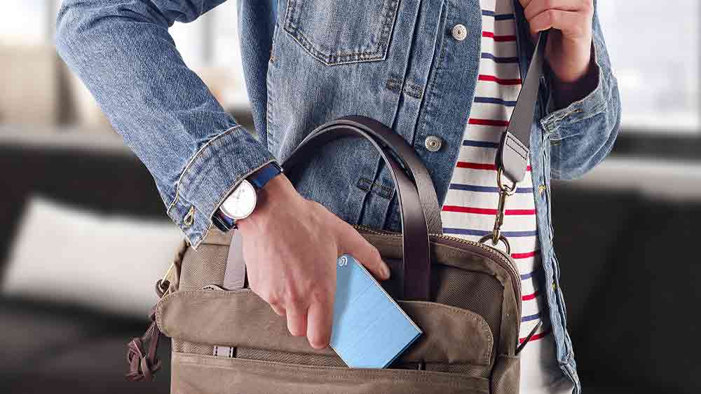 Člověk vkládající disk Seagate One Touch do tašky_02