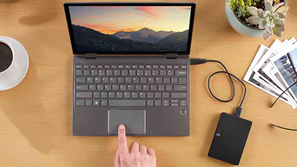 Muž ovládající notebook, do kterého je zapojený HDD disk Seagate Expansion Portable_02