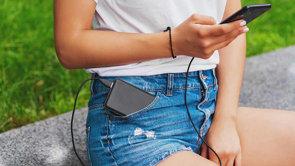 Dívka nabíjí svůj telefon powerbankou v kapse_03