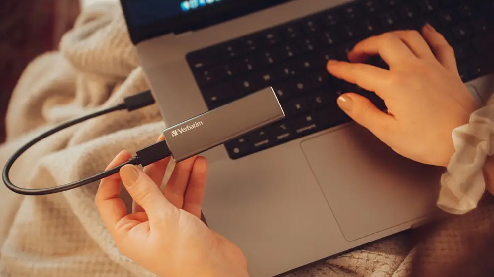 Žena pripojuje k notebooku externý SSD disk Verbatim Vx500_02