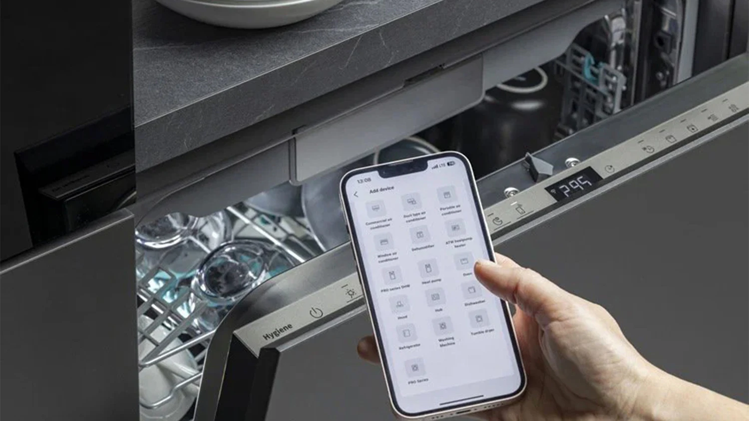 Myčka Hisense v pozadí a ruka s telefonem s aplikací ConnectLife
