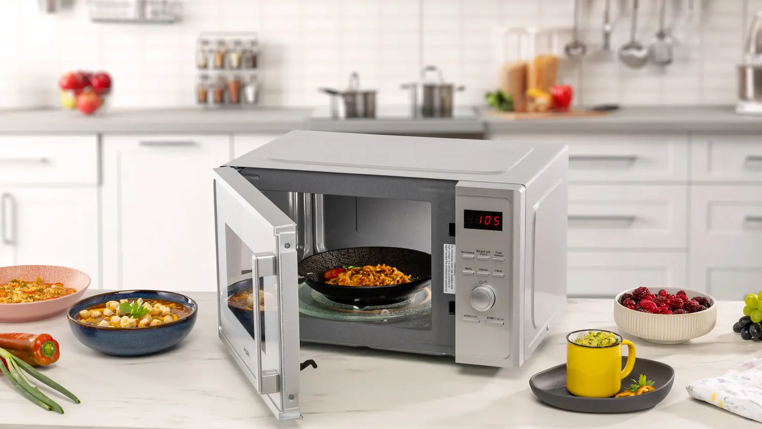 Otevřená mikrovlnná trouba MORA MT 423 S s talířem uvnitř a další pokrmy položené vedle ní