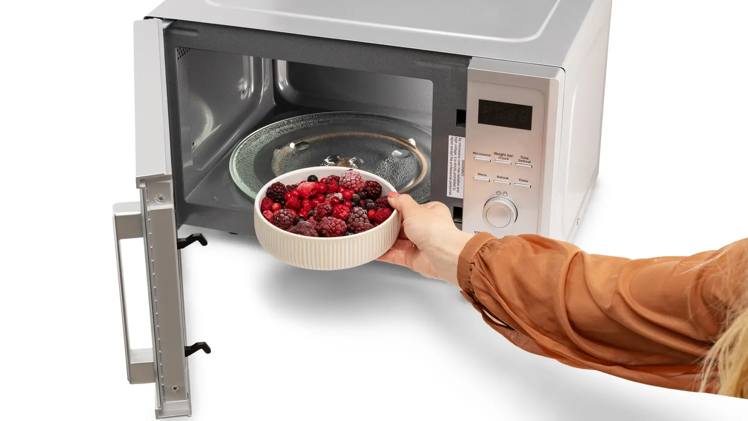 Ženská ruka vkládá do mikrovlnné trouby MORA MT 423 S misku s mraženým ovocem