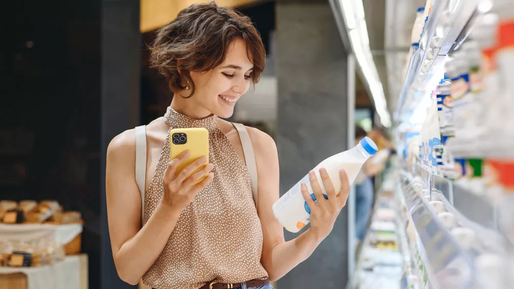 Žena s mobilem vyb&iacute;r&aacute; potraviny v supermarketu_05