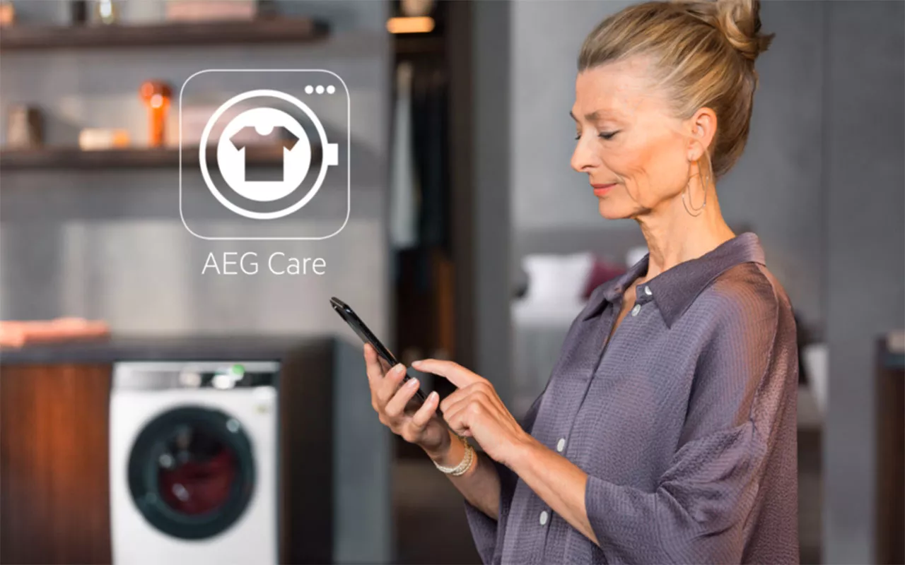 Žena ovl&aacute;d&aacute; telefonem pračku se su&scaron;ičkou AEG LWR85165OC_05