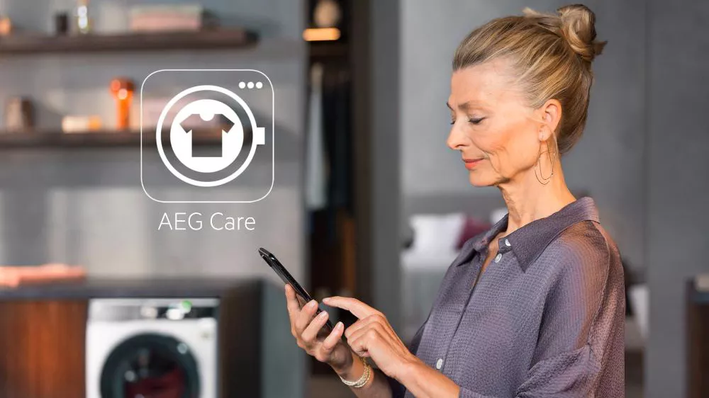Žena ovl&aacute;d&aacute; mobiln&iacute;m telefonem pračku se su&scaron;ičkou AEG LWR85865OC_02
