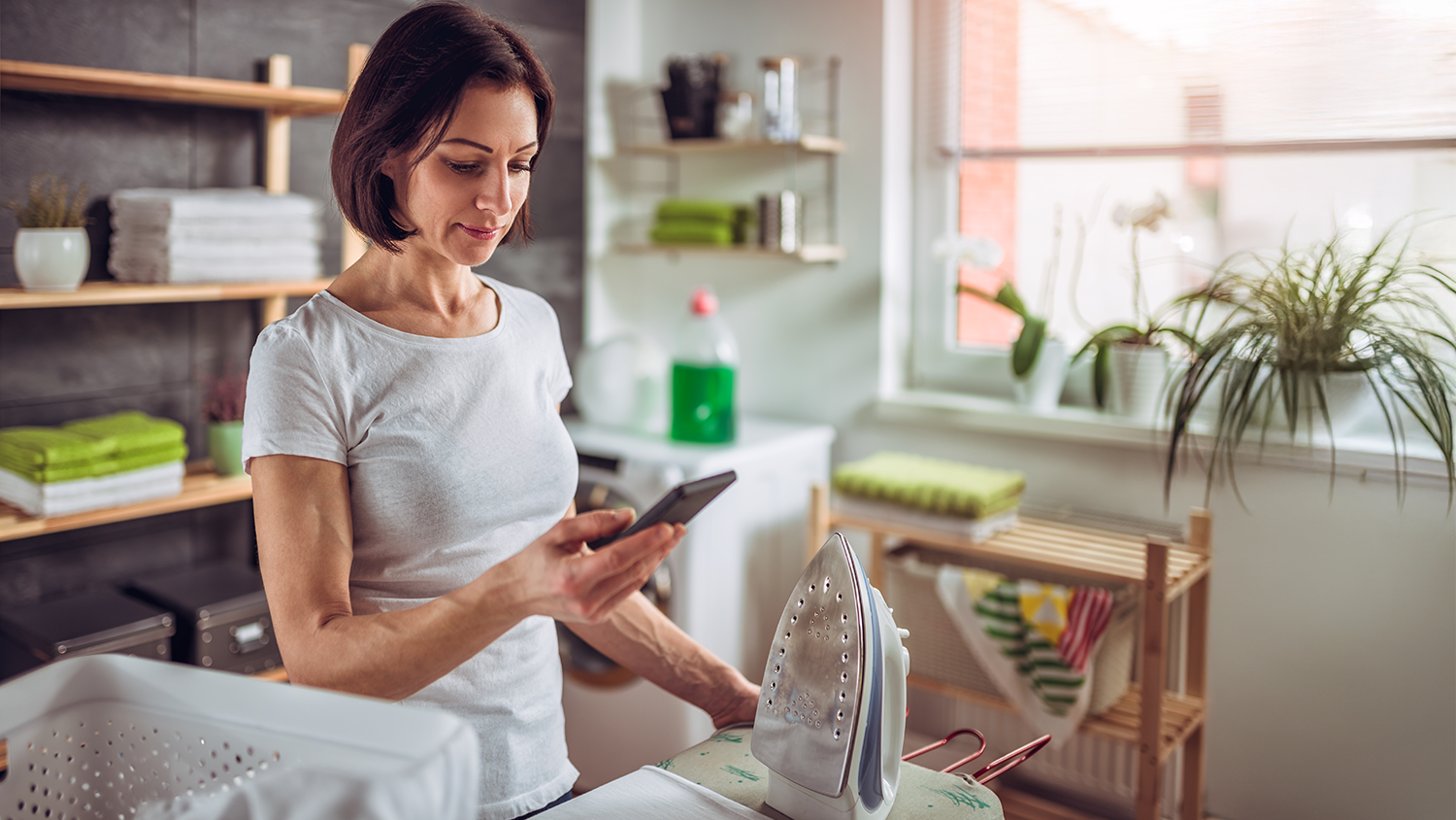 Žena s mobilom pri žehliacej doske