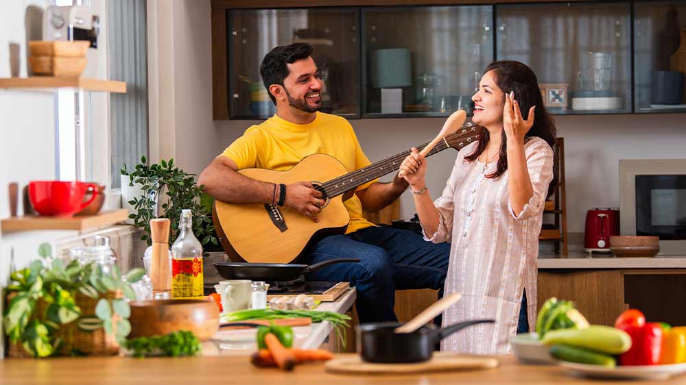 Muž so ženou pri varení spievajú a hrajú na gitare_04