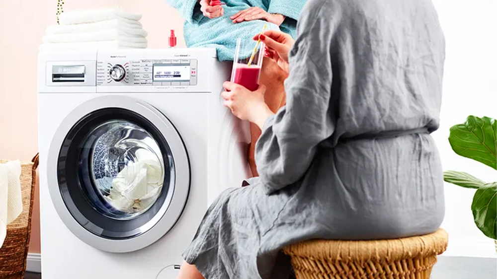 Žena sedí u kombinované pračky se sušičkou BOSCH WNG254A0BY_02