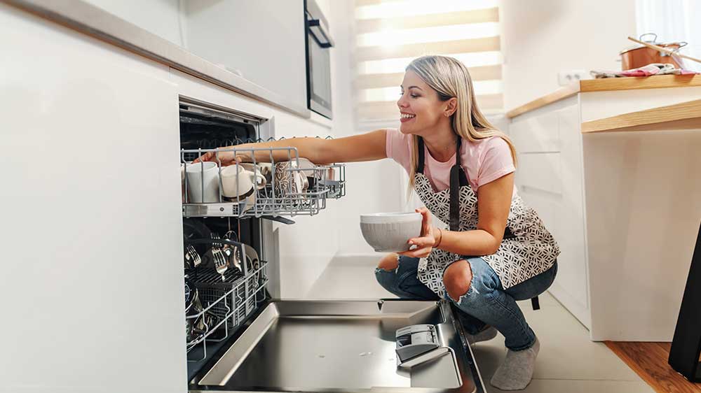 Žena s úsměvem vkládá nádobí do myčky_02