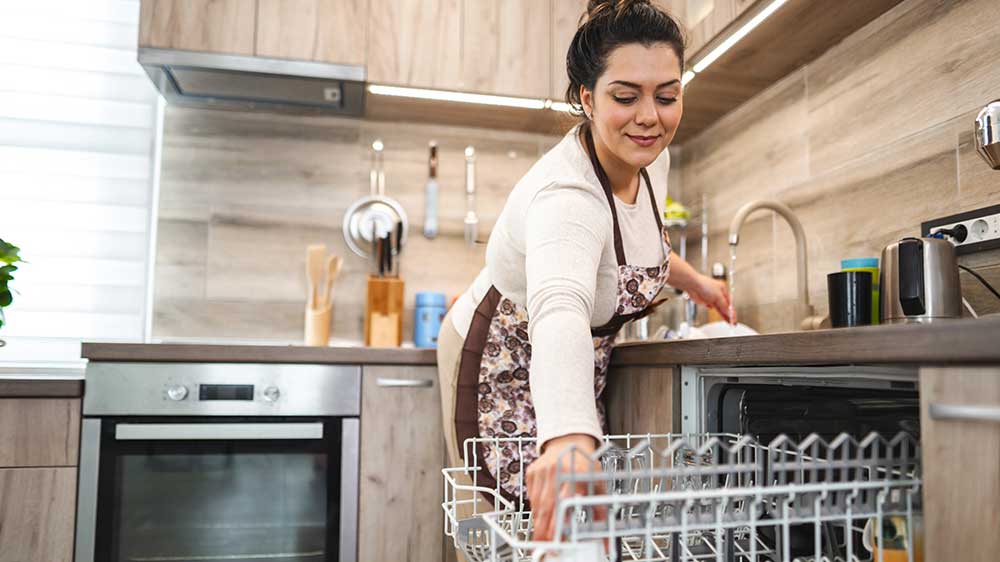 Žena s úsměvem vkládá nádobí do vestavné myčky_04