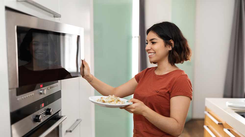Žena vkládá jídlo do mikrovlnné trouby_03