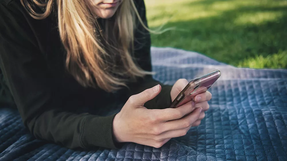 Žena drž&iacute;c&iacute; telefon ovl&aacute;daj&iacute;c&iacute; su&scaron;ičku na d&aacute;lku_04