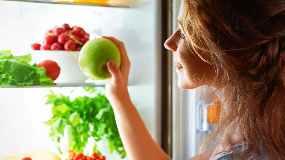 Žena si s úsměvem bere ovoce z lednice_02