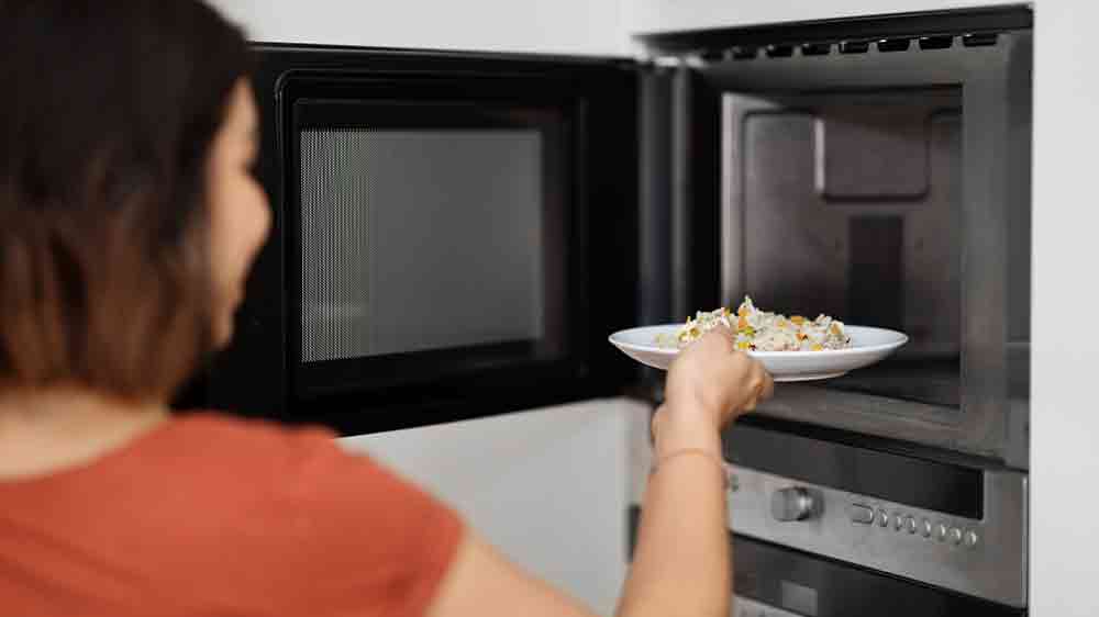Žena dává jídlo do mikrovlnné trouby_02