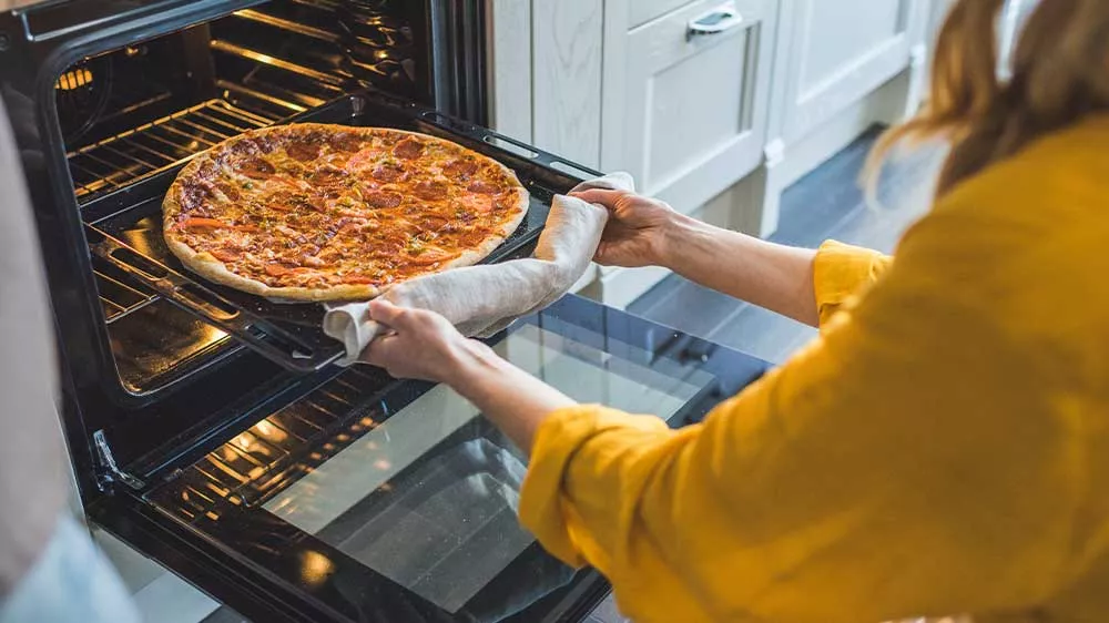 Žena vyndává z trouby plech s upečenou pizzou_05