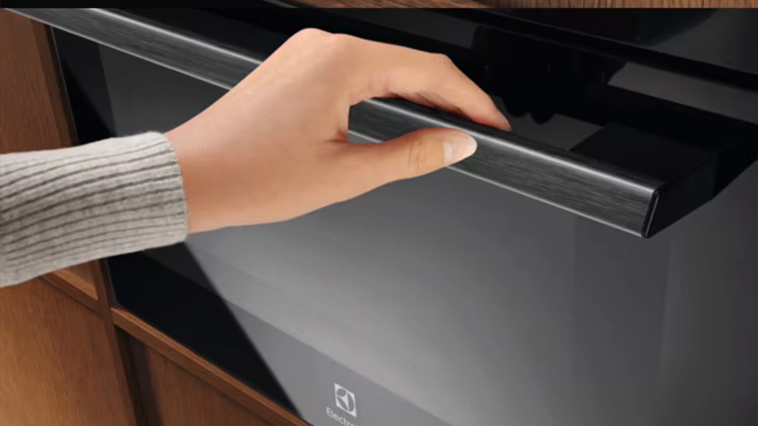 Ženská ruka otevírá vestavnou troubu Electrolux LVM9E2XZ.