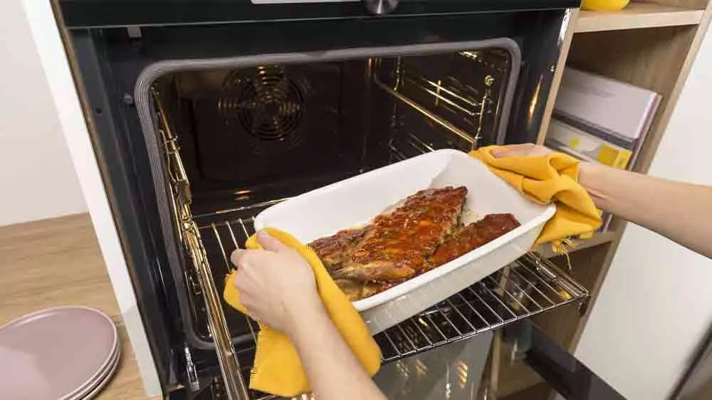 Člověk vytahující pekáč s masem z trouby Gorenje _05