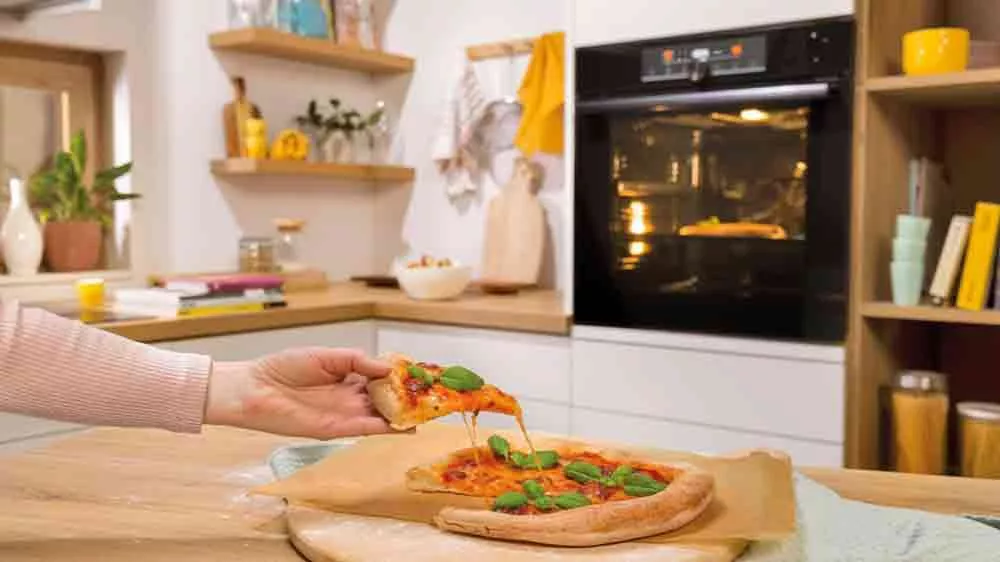 Žena si bere pizzu upečenou v multifunkční troubě Gorenje_03