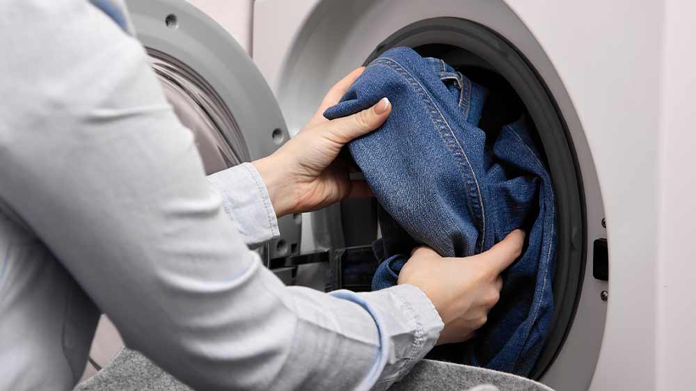 Ženské ruce vyndávající džíny z pračky_04