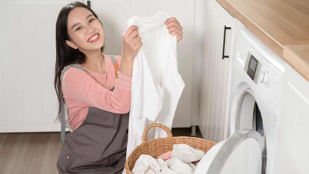 Žena před pračkou v podřepu, která se raduje z čistého bílého prádla_06