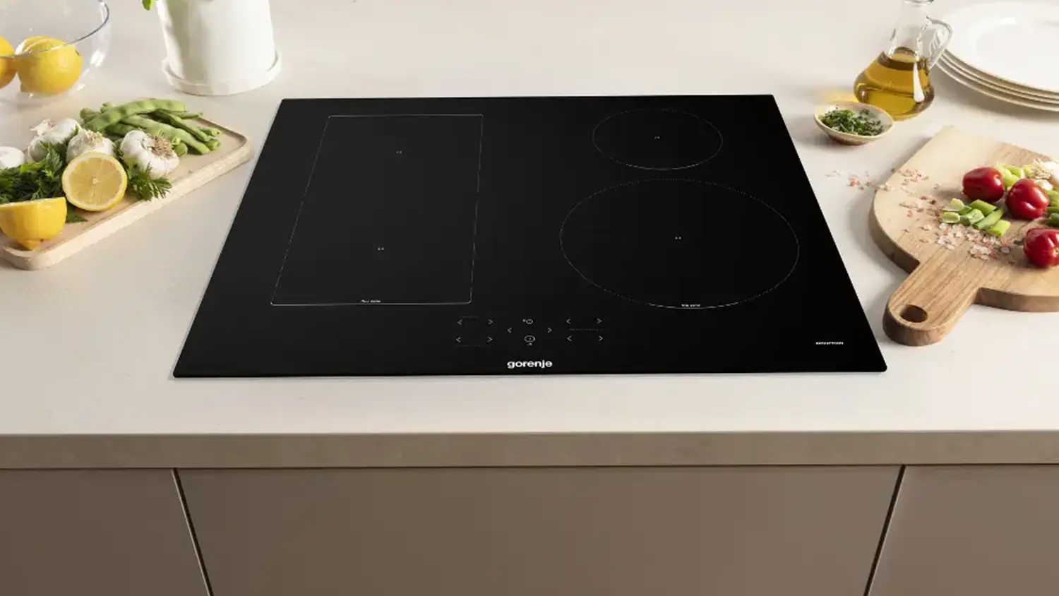 Indukční varná deska Gorenje GI6431BFZ zapuštěná v lince a vedle zelenina na prkénku
