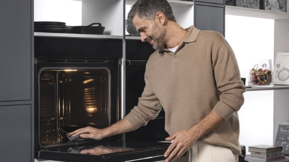 Muž utírá vestavnou horkovzdušnou troubu Haier H6 ID66C3YTB_05