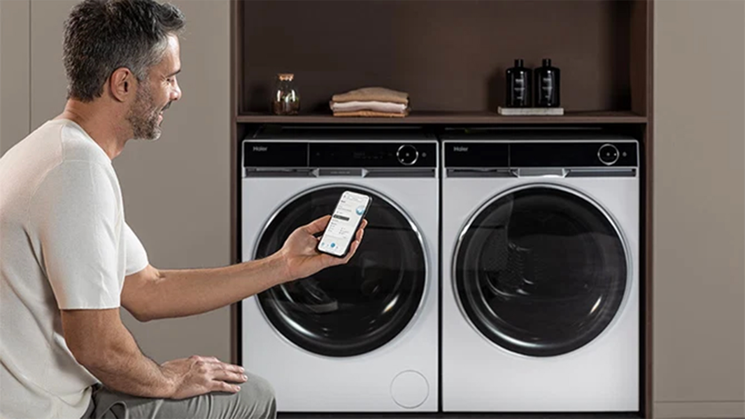 Muž s mobilom pred práčkou a sušičkou Haier