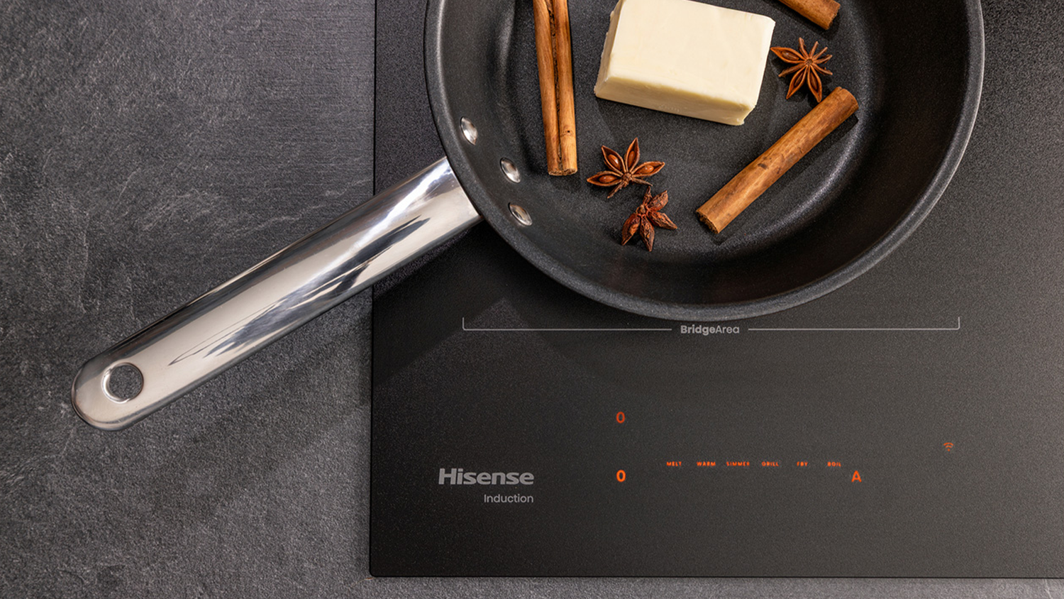 P&aacute;nev na indukčn&iacute; desce Hisense HI6443SRWF, ve kter&eacute; je m&aacute;slo, skořice a bady&aacute;n