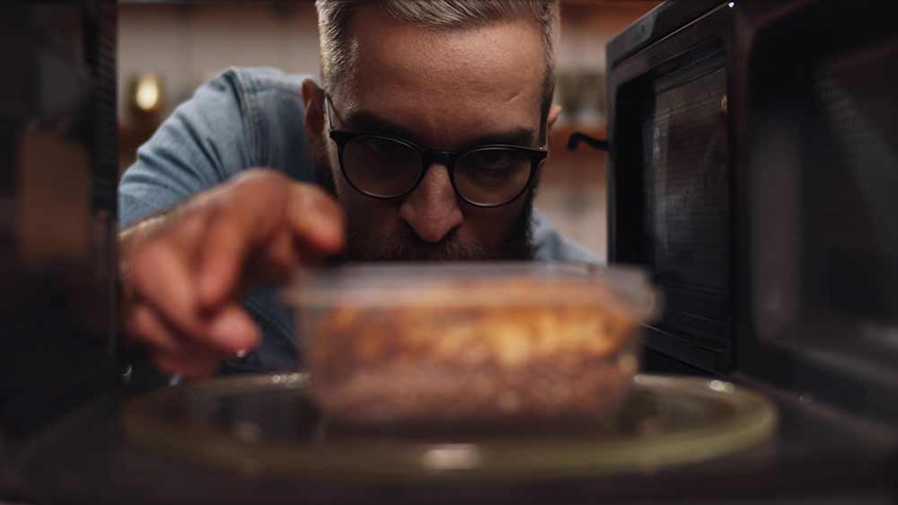 Muž vytahující jídlo z mikrovlnné trouby_03