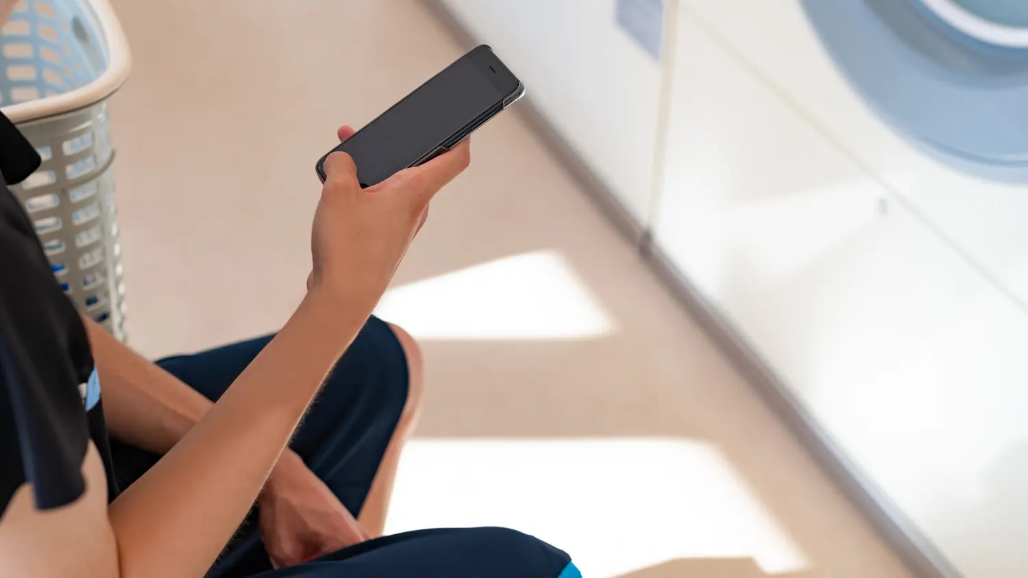 žsk&aacute; ruka drž&iacute; telef&oacute;n pri su&scaron;ičke bielizne