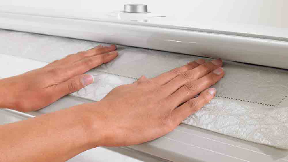 Žensk&eacute; ruce přidržuj&iacute; pr&aacute;dlo v mandlu Miele B 995 D_03