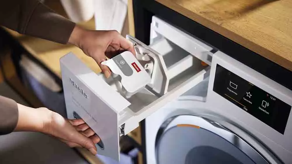 Žena vkl&aacute;d&aacute; impregnačn&iacute; prostředek Miele Caps ImpraProtect WA CIP 0302 L do pračky_03