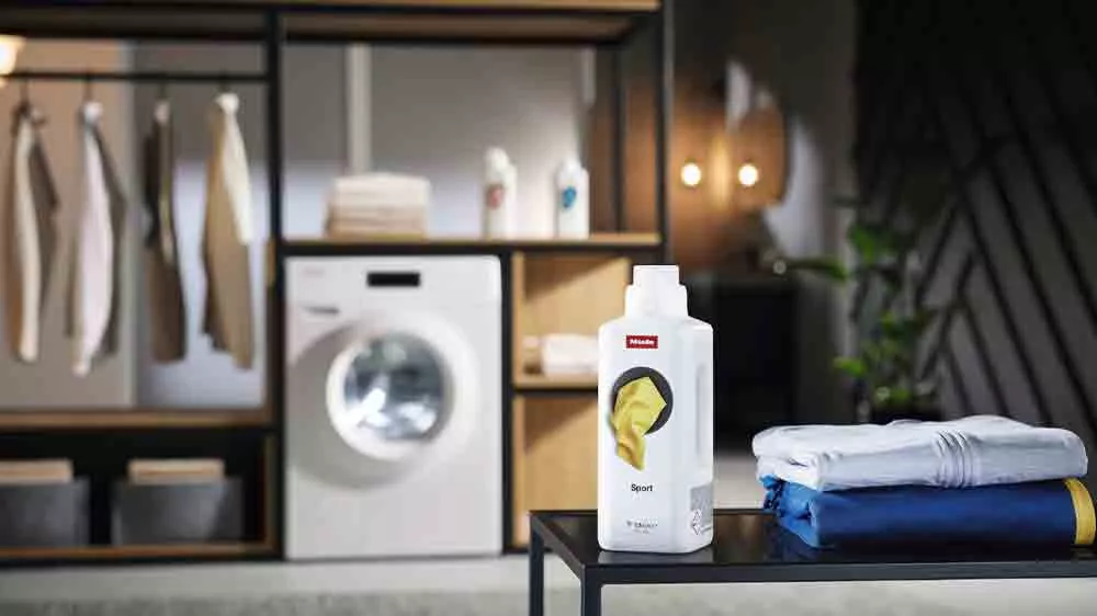 Speci&aacute;ln&iacute; prac&iacute; prostředek Miele Sport 1,5 l WA SP 1501 stoj&iacute;c&iacute; na stolečku v &scaron;atně před pračkou_02