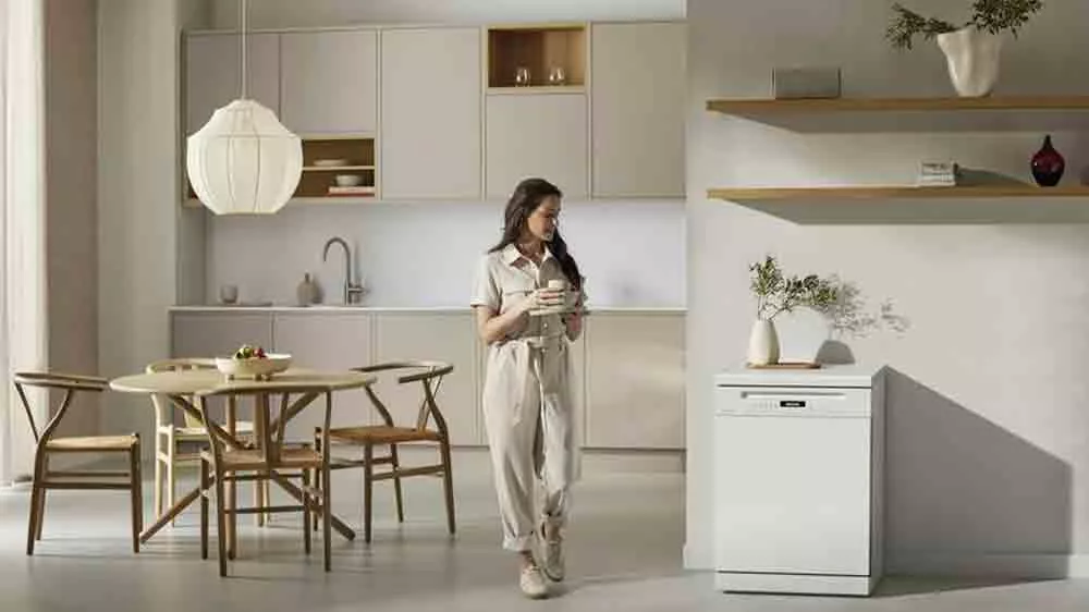 Žena s n&aacute;dob&iacute;m v ruce proch&aacute;z&iacute; kolem myčky Miele G 7210 SC_04