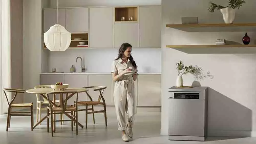 Žena s n&aacute;dob&iacute;m v ruce proch&aacute;z&iacute; kolem myčky Miele G 7600 SC_04