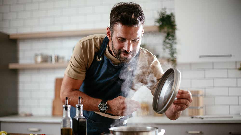 Muž naklánějící se nad hrnec a nadzvedávající pokličku_03