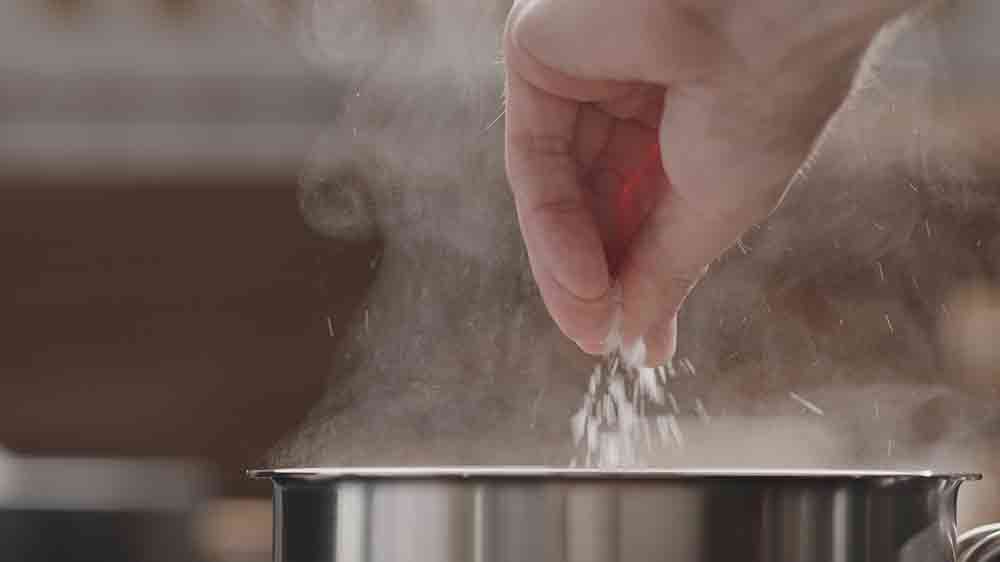 Muž solí vroucí vodu v hrnci_03