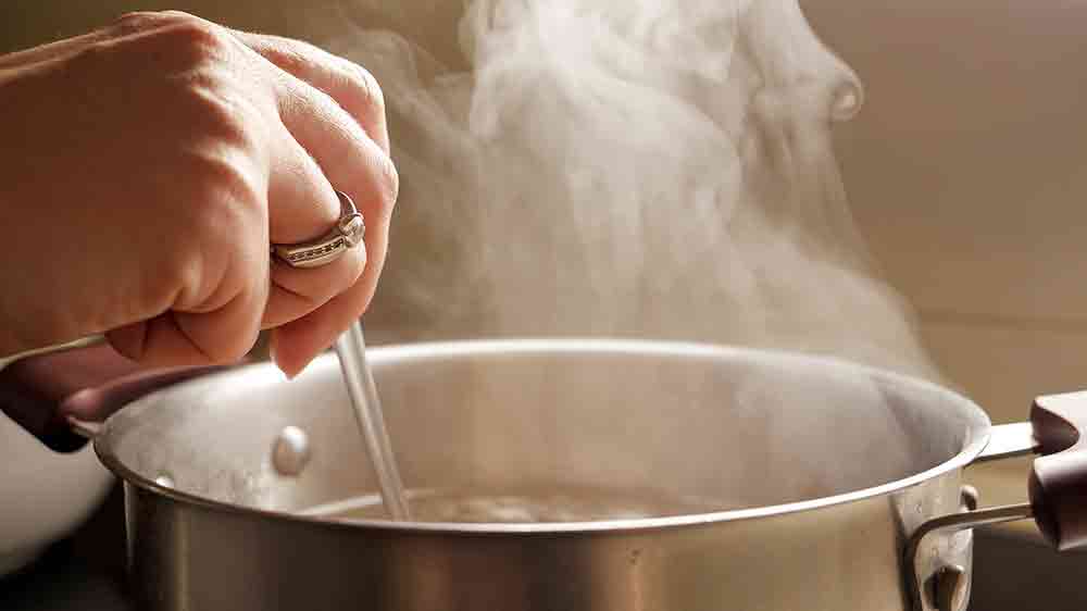 Žena míchá jídlo v hrnci, nad kterým stoupá pára_02