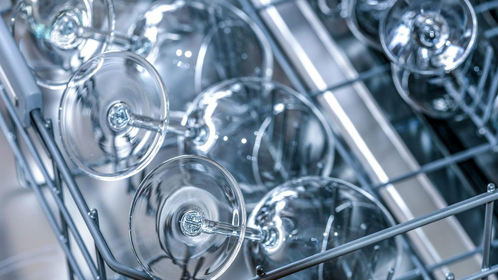 Čisté sklenky na víno ve vysunutém koši myčky nádobí