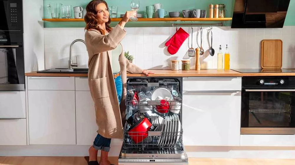 Žena kontroluje umytou sklenku z myčky nádobí Mora SM585W_04