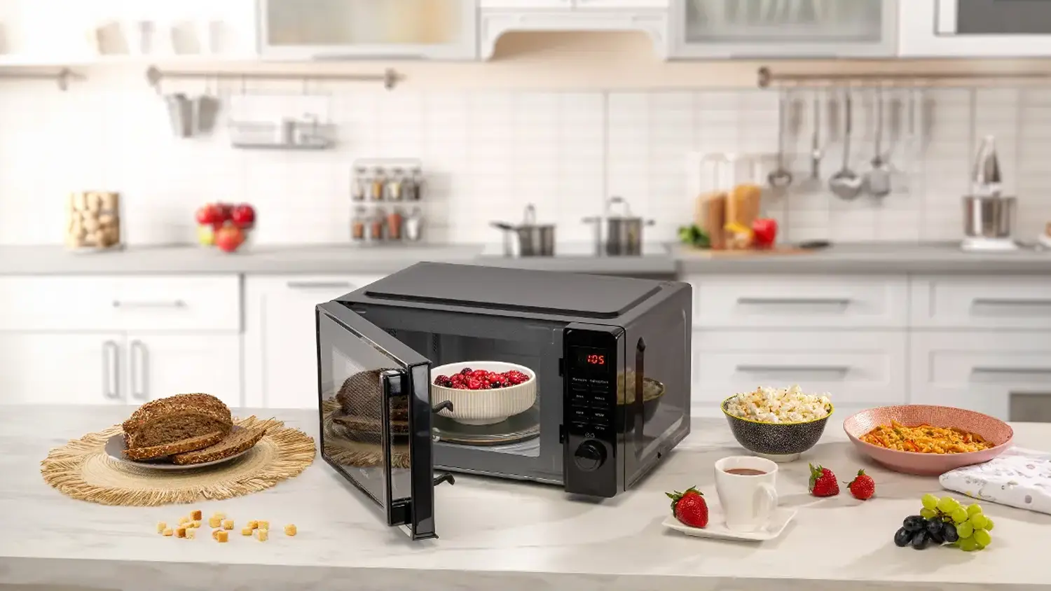 Miska s rozmrazen&yacute;m ovocem v mikrovlnn&eacute; troubě MORA a hotov&yacute; popcorn a dal&scaron;&iacute; j&iacute;dlo stoj&iacute;c&iacute; vedle na kuchyňsk&eacute; lince