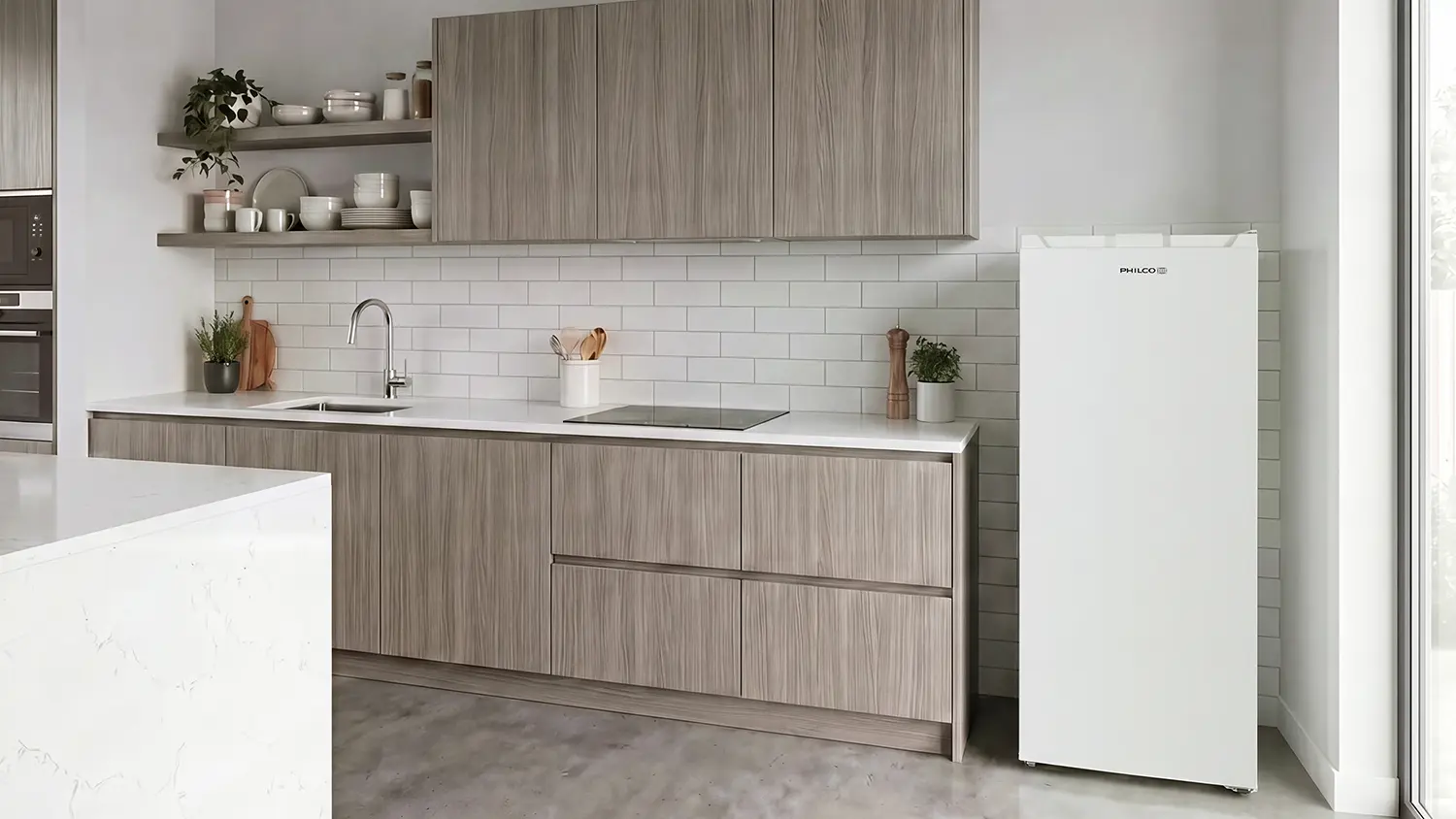 Šuplíkový volně stojící mrazák Philco PF 161 DNFIW postavený vedle kuchyňské linky.