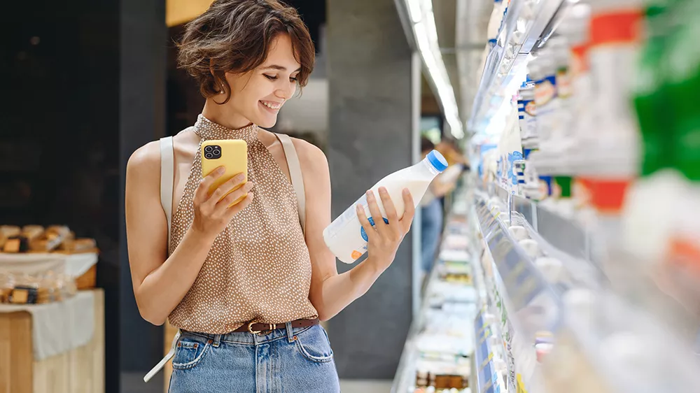 Žena s mobilem vyb&iacute;r&aacute; potraviny v supermarketu_06