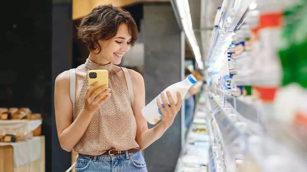 Žena s mobilem vyb&iacute;r&aacute; potraviny v supermarketu_05