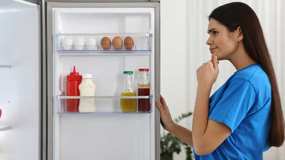 Mladá žena nahlíží do ledničky_02