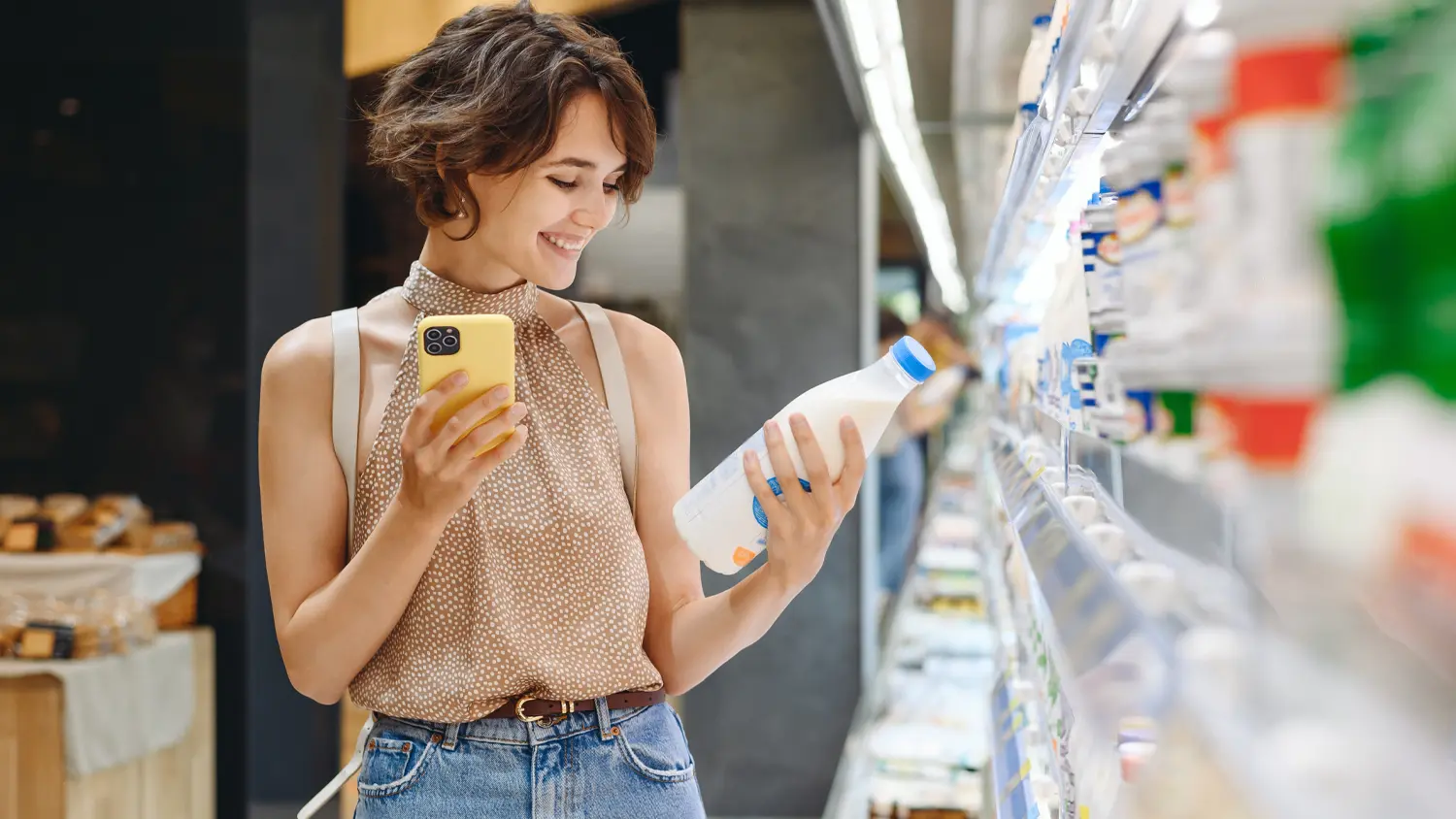 Žena s mobilom vyber&aacute; potraviny v supermarkete